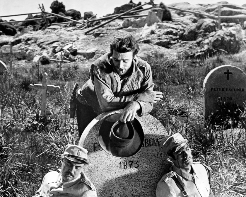 Joe, played by American actor Clint Eastwood, contemplates two dead soldiers in a graveyard in a promotional still for 'A Fistful of Dollars', directed by Sergio Leone, 1964. (Photo by Silver Screen Collection/Getty Images)