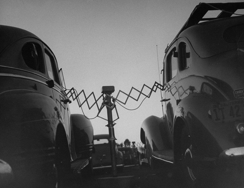 Cars parked at Rancho Drive-In Theater w. the accordion-like fulcrum arms of movie speakers reaching into each driver's front window, which they will push back onto the central post when the movie is over. (Photo by Allan Grant/The LIFE Picture Collection/Getty Images)