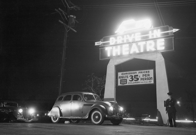 5/21/1938-Los Angeles, CA-ORIGINAL CAPTION READS: Motoring and motion pictures achieve a happy wedding in the Drive-In Theater of Los Angeles. The theater is a parking lot with graduated tiers from which motorists, seated in their own cars, watch the films projected on a giant screen. Synchronized amplifiers in front of each automobile make speech audible in all parts of the lot. Here's a view of the entrance to the theater with customers about to drive in.