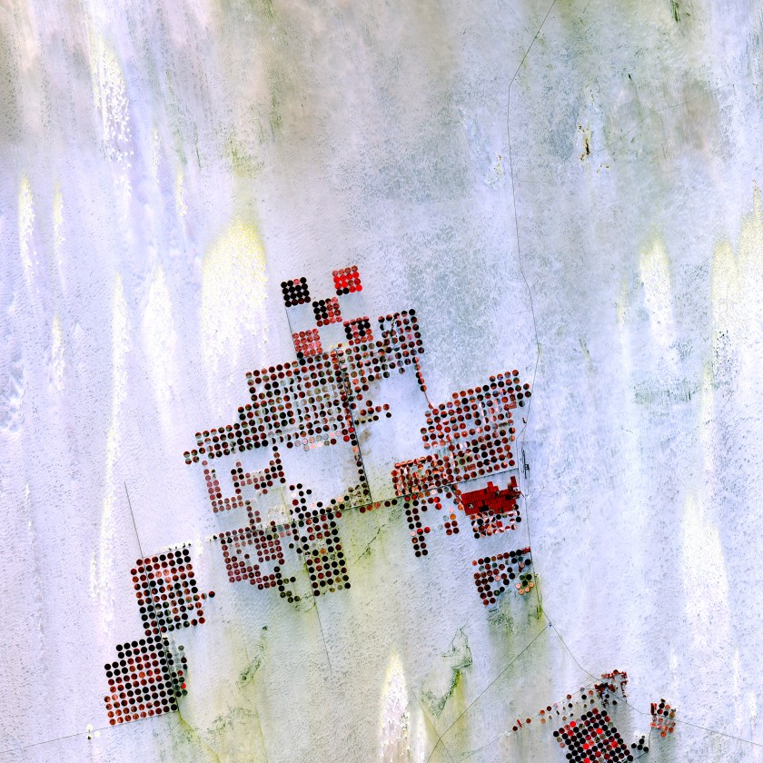 Geometric shapes lie across the emptiness of the Sahara Desert in southern Egypt. Each point is a center pivot irrigation field a little less than 1 kilometer (0.6 mile) across. With no surface water in this region, wells pump underground water to rotating sprinklers from the huge Nubian Sandstone aquifer, which lies underneath the desert. (USGS/NASA)