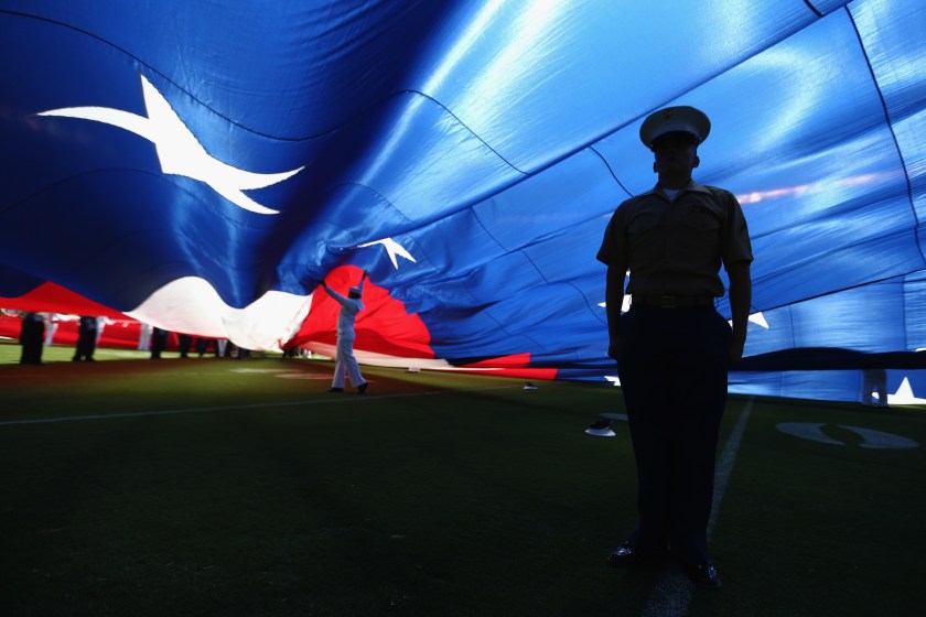 A U.S. Marine stands at attention under a large American flag before a game between the Jacksonville Jaguars and the San Diego Chargers at Qualcomm Stadium on September 18, 2016 in San Diego, California. (Sean M. Haffey/Getty Images)