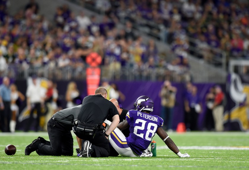 Adrian Peterson #28 of the Minnesota Vikings sits on the field as trainers tended to his knee in the third quarter of the game against the Green Bay Packers on September 18, 2016 at US Bank Stadium in Minneapolis, Minnesota. Peterson was carried to the sidelines and later went to the locker room. (Hannah Foslien/Getty Images)