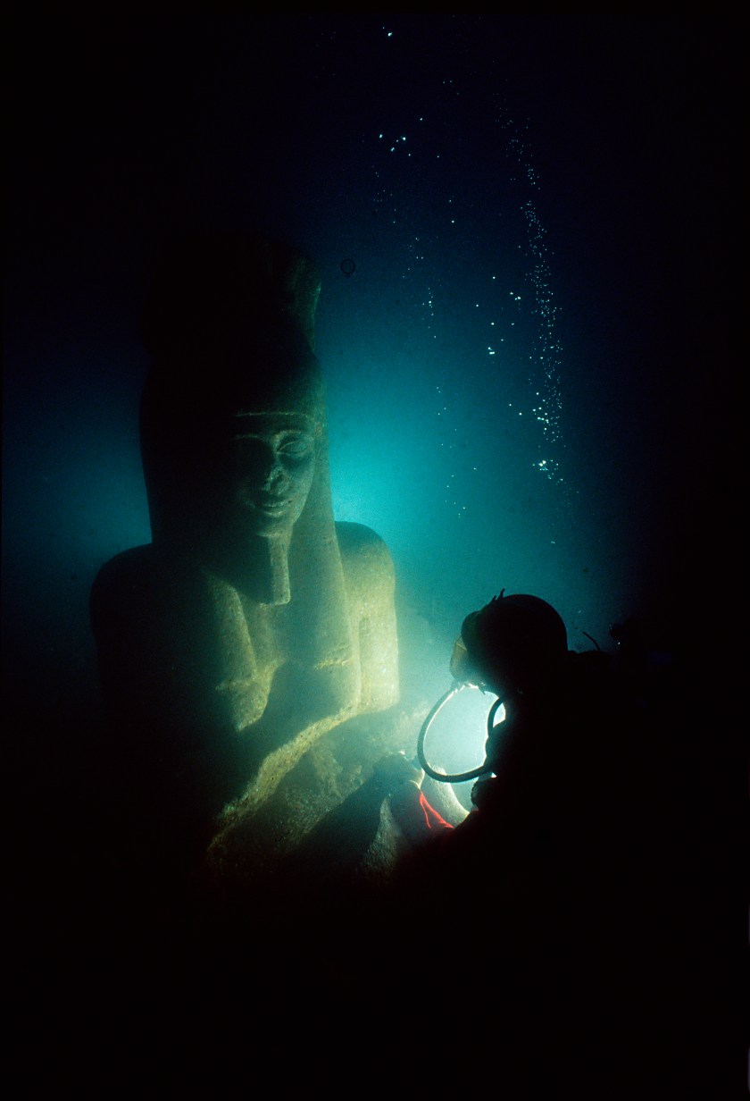 A colossal statue of red granite (5.4 m) representing the god H apy, which decorated the temple of Thonis-Heracleion. The god of the flooding of t he Nile, symbol of abundance and fertility, has never before been discovered at such a large scale, which points to his importance for the Canopic region. Height 5.4 metres, depth 90 centimetres, weight 6 tonnes. Early Ptolemaic period, 4th century BC. (Franck Goddio/Hilti Foundation)