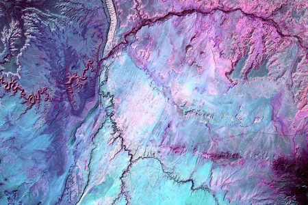 What looks like lightning arcing through an ominous cloud is actually a dry landscape of rocky buttes in southern Utah and northeastern Arizona. River channels flow north from Arizona into the San Juan River. The light vertical feature at the top of the image is referred to as Comb Ridge, a jagged fold in the Earth's crust called a monocline. (USGS/NASA)