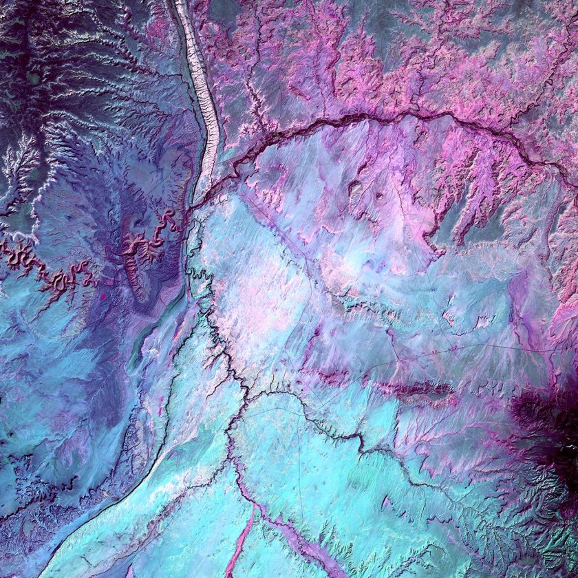 What looks like lightning arcing through an ominous cloud is actually a dry landscape of rocky buttes in southern Utah and northeastern Arizona. River channels flow north from Arizona into the San Juan River. The light vertical feature at the top of the image is referred to as Comb Ridge, a jagged fold in the Earth's crust called a monocline. (USGS/NASA)