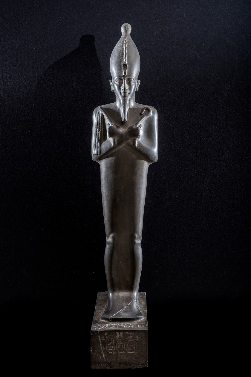 Standing image of Osiris wearing the white crown, uraei and r egalia (Grey-green Graywacke, H. 1.50 m). This masterpiece of Saite statuary carries a dedi cation from the ͞ divine adorer of Amun ͟ Nitocris, daughter of Psamtik I (664-610 BC).The look of the ͞ Lord of Life ͟ seems fixed on a point beyond space and time, and his entire bei ng radiates an intense energy of life. (Franck Goddio/Hilti Foundation)