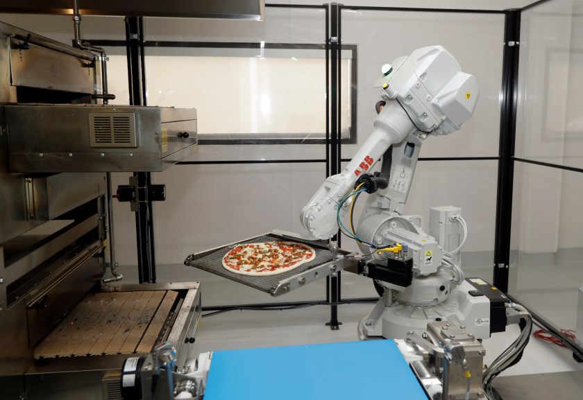 In this Monday, Aug. 29, 2016 photo, a robot places a pizza into an oven at Zume Pizza in Mountain View, Calif. The startup, which began delivery in April, is using intelligent machines to grab a slice of the multi-billion-dollar pizza delivery market. Zume is one of a growing number of food-tech firms seeking to disrupt the restaurant industry with software and robots that let them cut costs, speed production and improve worker safety. (AP Photo/Marcio Jose Sanchez)