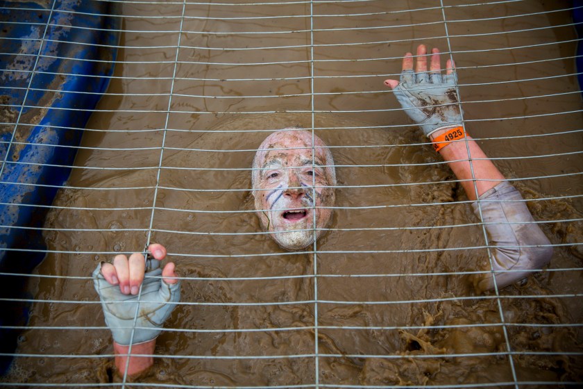 Competitors crawl in a cage filled with muddy water while challenging in Tough Mudder endurance race in Henley-on-Thames, England on 27 April, 2014. (Tolga Akmen/Anadolu Agency/Getty Images)