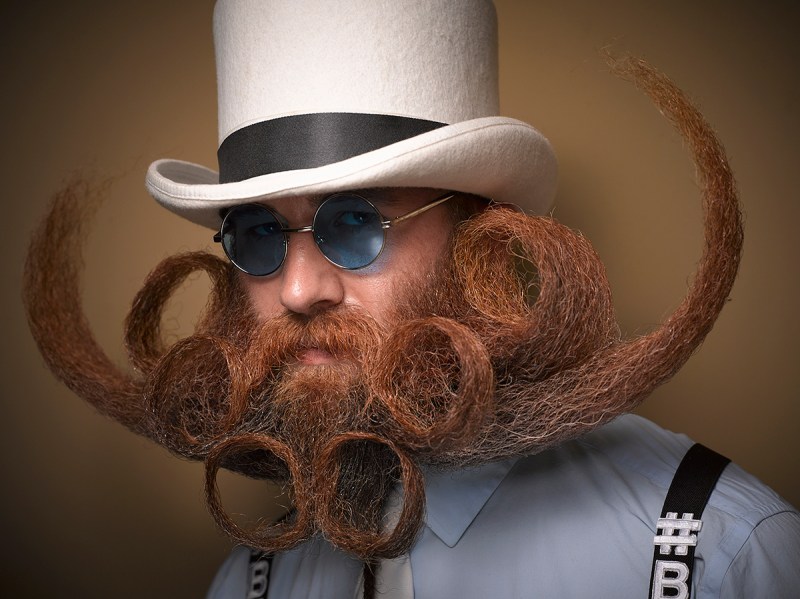 PIC BY GREG ANDERSON / CATERS NEWS - (PICTURED: A contestant of the beard championship with a curly beard.) - Gents from around the world descended on Nashville earlier this month fighting for the title of best beard in the National Beard and Moustache Championship. The annual competition covers 17 categories in which the men can compete, ranging from freestyle, to natural, to facial hair inspired by icons such as Dali and the Musketeers. With the competition as stiff as the waxed moustaches, competitors had to go beard to beard to decide whose facial fuzz was the most fan-TASH-tic. Competitors were judged on their overall appearance, style and personality, with judges also considering originality and creativity in the freestyle categories. Contestants certainly rose to the challenge with perfectly curled beards and also more outrageous statement styles, such as a Tim Burton themed beard, and a beard styled to look like a beak. - SEE CATERS COPY