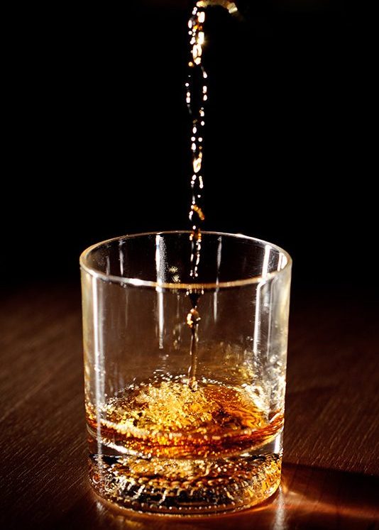 Scotch or bourbon whiskey (or whisky) being poured into a glass with dramatic studio lighting and a black background. (Getty Images)