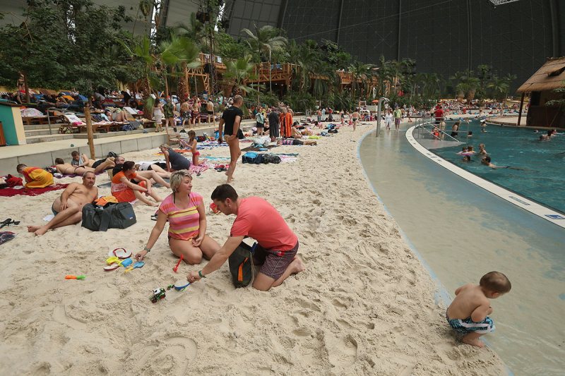 KRAUSNICK, GERMANY - FEBRUARY 15: A couple from the east German city of Chemnitz lounge with their son at the "South Sea" beach at the Tropical Islands indoor resort on February 15, 2013 in Krausnick, Germany. Located on the site of a former Soviet military air base, the resort occupies a hangar built originally to house airships designed to haul long-distance cargo. Tropical Islands opened to the public in 2004 and offers visitors a tropical getaway complete with exotic flora and fauna, a beach, lagoon, restaurants, water slide, evening shows, sauna, adventure park and overnights stays ranging from rudimentary to luxury. The hangar, which is 360 metres long, 210 metres wide and 107 metres high, is tall enough to enclose the Statue of Liberty. (Photo by Sean Gallup/Getty Images)