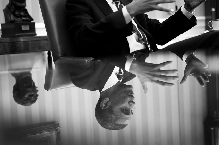 "The President is reflected in a glass table top during a meeting in the Oval Office." (Official White House Photo by Pete Souza)