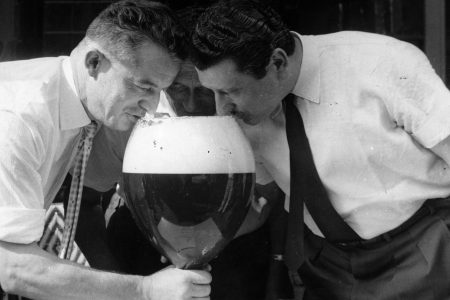 circa 1960:  Three men drinking from a large glass of beer.  (Photo by Keystone/Getty Images)