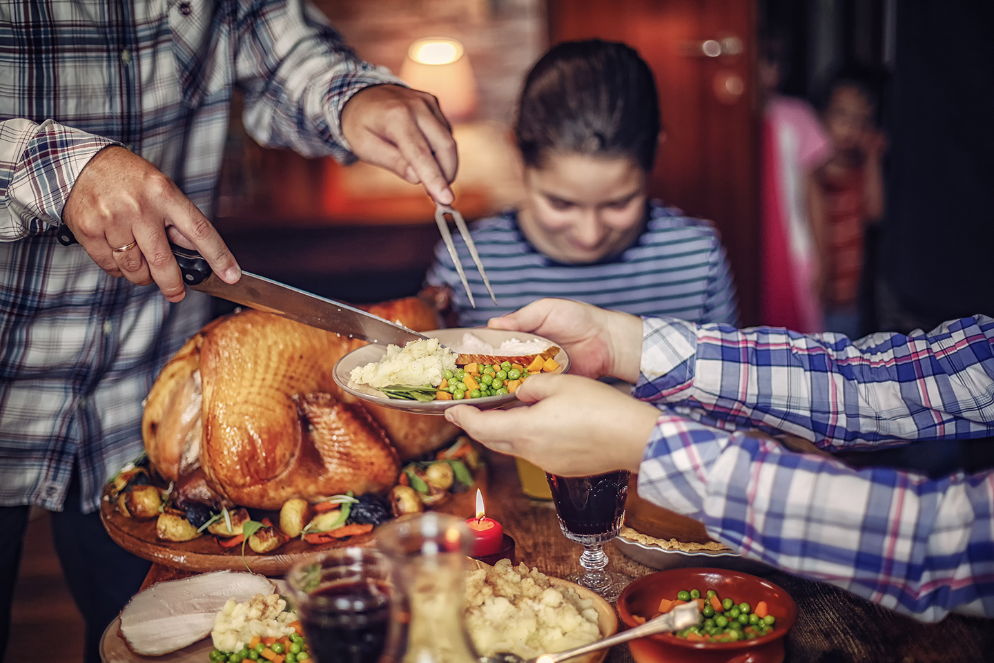 Carving traditional stuffed turkey and serving it with mashed potatoes, cranberry sauce, vegetables and pumpkin pie.