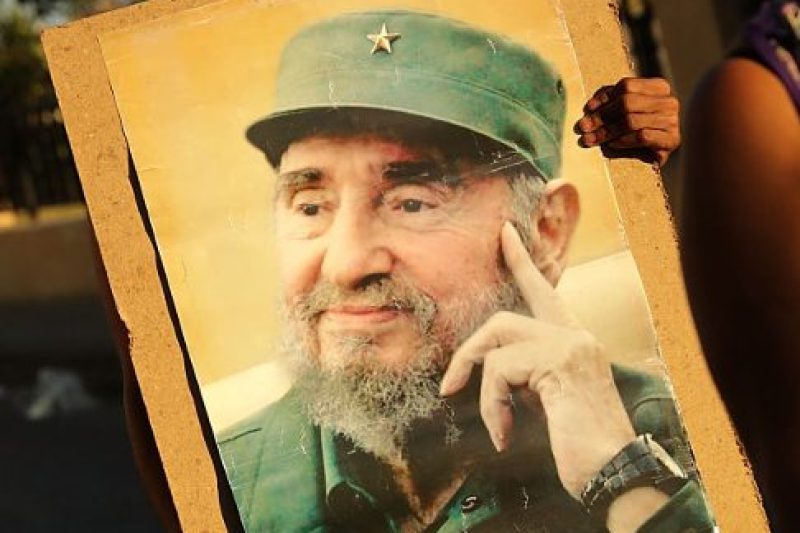 A woman carries a poster with the image of former Cuban President Fidel Castro after thousands of Cubans lined the famous Malecon seaside boulevard to pay their respects as his remains began their journey across the country (Chip Somodevilla/Getty Images)