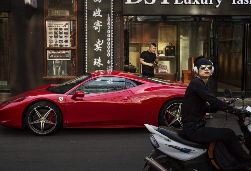 A Chinese man stands next to his luxury car as its is parked in an upscale shopping district on May 29, 2015 in Beijing, China. China is expected to become the world's largest luxury car market by 2016, analysts say. (Kevin Frayer/Getty Images)