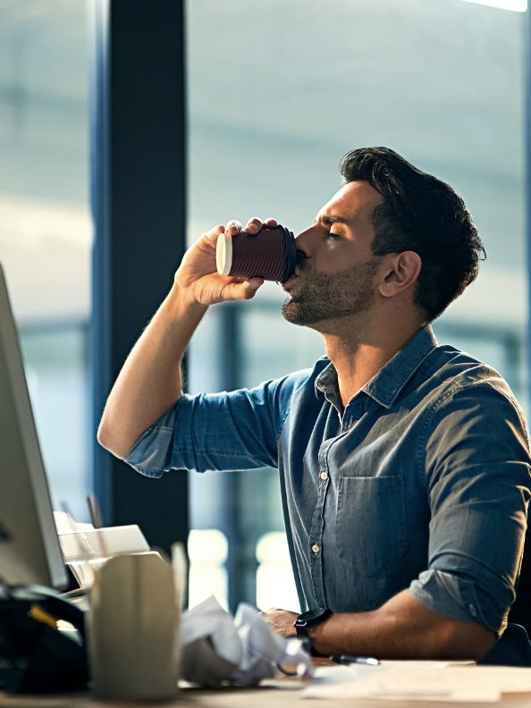 Shot of a young businessman drinking coffee during a late night at work (PeopleImages)