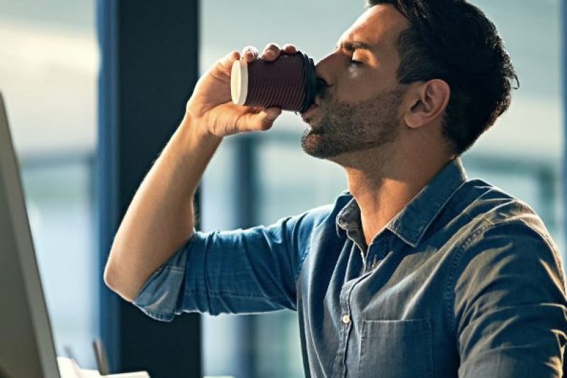 Shot of a young businessman drinking coffee during a late night at work (PeopleImages)