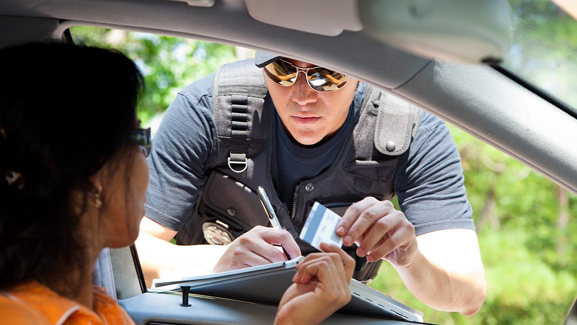 A police officer stops a driver to give her a traffic ticket for speeding. (Getty Images)