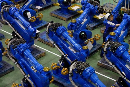 An employee inspects Yaskawa Electric Corp. Motoman robots bound for shipment at the company's factory in Kitakyushu, Japan, on Thursday, July 16, 2015. (Akio Kon/ Bloomberg)