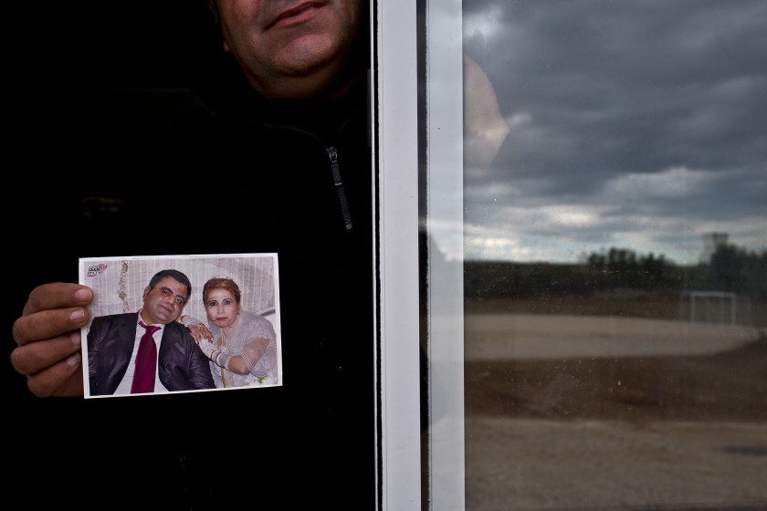 In this Thursday, Jan. 5, 2017 photo, Henef Slu, 37, a Syrian refugee from Aleppo's northern district of Sheikh Maqsud, holds a photograph of his wedding day, from the window of his shelter in Ritsona refugee camp, Greece. "It was the most beautiful day of my life the day I married my wife Nadima, we had a lot of guests, family and friends, this photograph was the only thing we carried with us from home." Henef said. (AP Photo/Muhammed Muheisen)