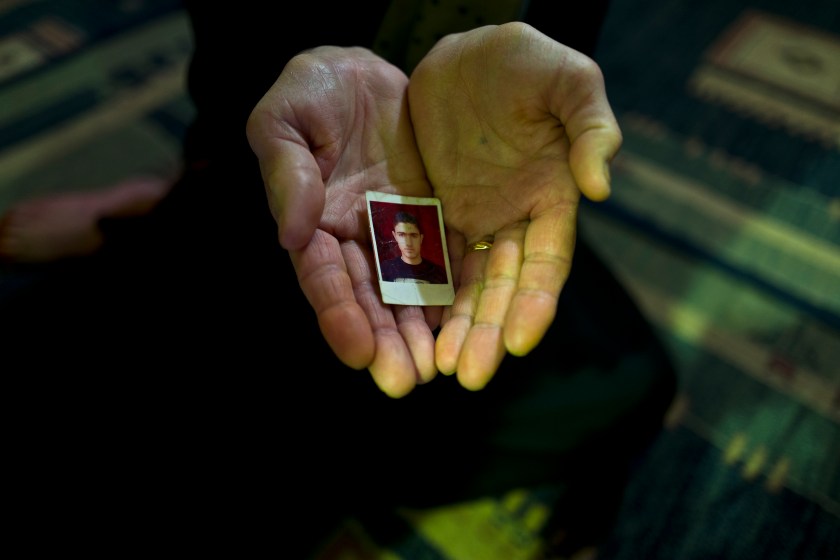 In this Tuesday, Jan. 17, 2017 photo, Suad Abdulmajeed, 57, a Syrian refugee from Al-Qamishly, shows a photograph of her son Ayaz, at her tent in Kalochori refugee camp on the outskirts of the northern Greek city of Thessaloniki. "We fled from Bashar, referring to the Syrian president, and the Islamic State with nothing but fear, we just wanted to be safe, my son and husband are in Germany and all I want is to be with them." Suad said. (AP Photo/Muhammed Muheisen)