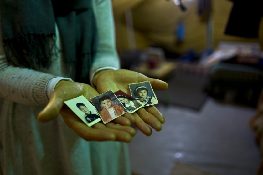 In this Tuesday, Jan. 17, 2017 photo, Sahar Dargzini, 40, a Syrian refugee from Baghdad street in Damascus, shows photographs of her children when they were young, from right, Amal who currently is 24 and lives in Norway, Dania who currently is 26 and lives in Turkey, Mohyeddin, whose currently 15 and lives in Sweden and Salahudin whose currently 20 and lives in Sweden, at her tent in Kalochori refugee camp on the outskirts of the northern Greek city of Thessaloniki. "I love keeping my children pictures with me all the times, they will always remain my children, I hope they will allow me to go to Norway and be with my daughter and see my granddaughter Mirna." Sahar said. (AP Photo/Muhammed Muheisen)