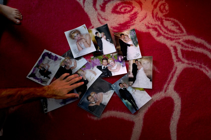 In this Wednesday, Jan. 11, 2017 photo, Sheikhmous Hussein, 33, a Syrian refugee from the northern district of Al-Ashrafiya, Aleppo, shows photographs from his wedding day, at his shelter in the refugee camp of Ritsona, Greece. "It was on the 8th of March 2014, these photographs were the only thing we managed to carry with us from Aleppo." Hussein said. (AP Photo/Muhammed Muheisen)