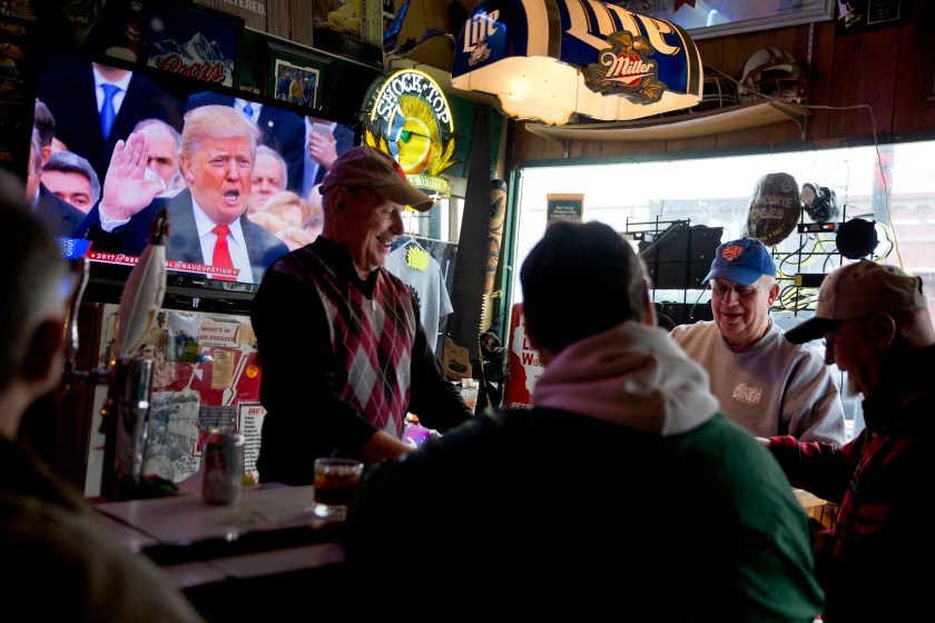 President Donald Trump is sworn in during a live broadcast of the inauguration as Denny Riebe, from right, Doug Dickman, Scott Reilly, and Bill Winter, play cards at the Sawmill Saloon in Prairie du Chien, Wis., Friday, Jan. 20, 2017. The men who meet here for cards every morning and call themselves the Corner of Superior Knowledge are made up democrats, Trump supporters and another described as agnostic. The campaign vitriol that has cleaved apart the country has not left the same scars here, a place where talking politics is considered impolite, where wives reported not knowing how their own husbands voted and husbands said they never asked their wives. (AP Photo/David Goldman)