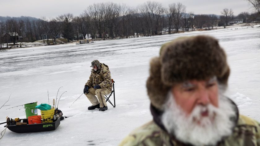 Trump voter Rick Trudo, foreground, ice fishes on a frozen portion of the Mississippi River.