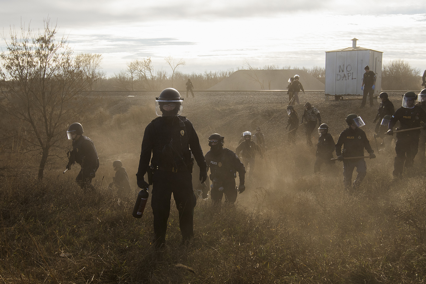 Contemporary Issues - First Prize, Stories: Riot police clear marchers from a secondary road outside a Dakota Access Pipeline (DAPL) worker camp using rubber bullets, pepper spray, tasers and arrests. In other incidents they've employed militarized vehicles, water canons, tear gas and have been accused of using percussion grenades. For nearly 10 months, members of the Standing Rock Sioux tribe and their allies camped out in opposition to the Dakota Access Pipeline crossing their territory and threatening their water supply. The estimated $3.78 billion project, backed by Energy Transfer Partners, is nearly complete, covering almost 1,172 miles. In military vehicles and body armor, police used tear gas, pepper spray, rubber bullets, and water cannons against the protesters, and have been accused of inhumane treatment of arrestees. (Amber Bracken)