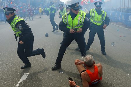 BOSTON - APRIL 15: Police officers with their guns drawn hear the second explosion down the street. The first explosion knocked down 78-year-old US marathon runner Bill Iffrig at the finish line of the 117th Boston Marathon. (Photo by John Tlumacki/The Boston Globe via Getty Images)