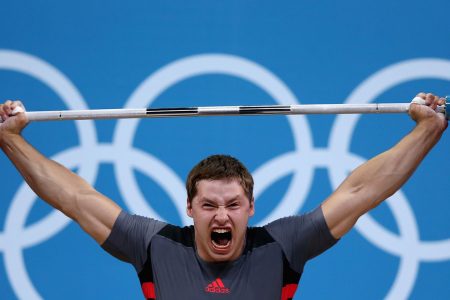 Professional weight lifter screaming while holding heavy weight