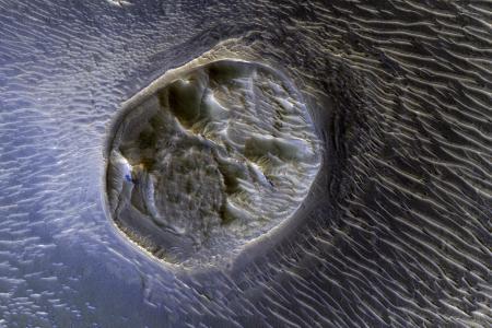 This image from NASA's Mars Reconnaissance Orbiter shows a small (0.4 kilometer) mesa, one of several surrounded by sand dunes in Noctis Labyrinthyus, an extensively fractured region on the western end of Valles Marineris. (NASA/Mars Reconnaissance Orbiter)