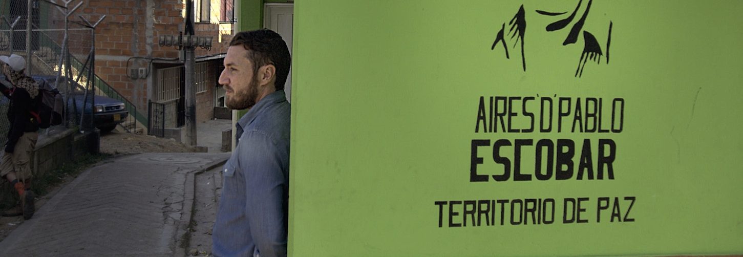 Doug Laux leans against a wall in the barrio with a stencil of Pablo Escobar's face spray-painted on its surface. (Courtesy of Discovery)