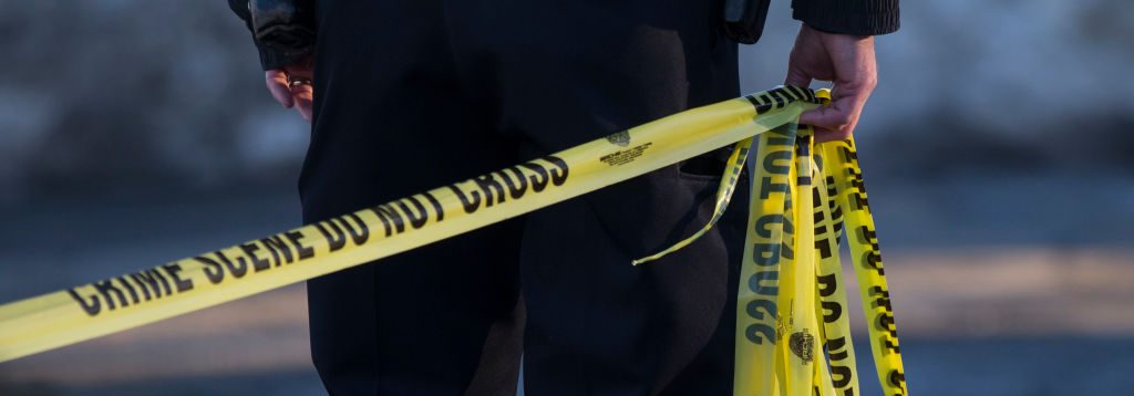 A police officer pulls crime scene tape at a house where a double homicide was being investigated in Peabody, MA on Feb. 19, 2017. (Keith Bedford/The Boston Globe via Getty Images)