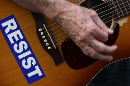 With his guitar adorned with a 'RESIST' sticker, a demonstrator plays music during a gathering to mark the 73rd anniversary of the Hiroshima and Nagasaki nuclear bombings, outside the Japanese Consulate in Midtown Manhattan, August 3, 2018 in New York City. (Photo by Drew Angerer/Getty Images)