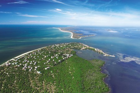 An aerial view of Sanibel Island in Florida at sunset, showing the Sanibel Lighthouse on the east end of the island. Here's why we think it's a great vacation destination.