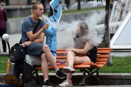 Young people smoke electronic cigarettes as they rest in the center of the Ukrainian capital of Kiev, on August 15, 2019. (Photo by Sergei SUPINSKY / AFP)        (Photo credit should read SERGEI SUPINSKY/AFP/Getty Images)