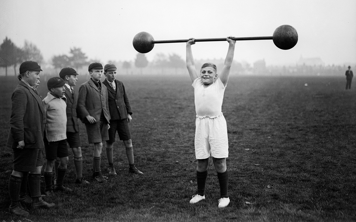 A young fellow lifting a barbell in the 1930s. Is he "stunting" his growth? 