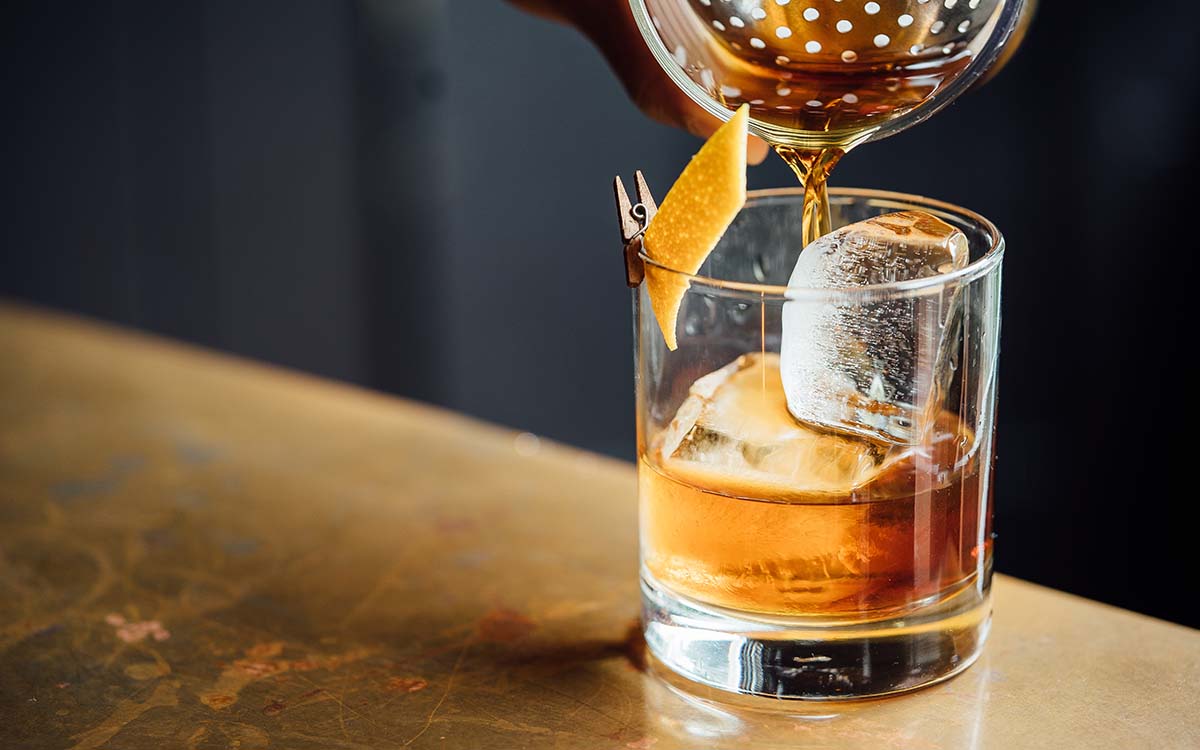 Straining a cocktail over ice into a rocks glass