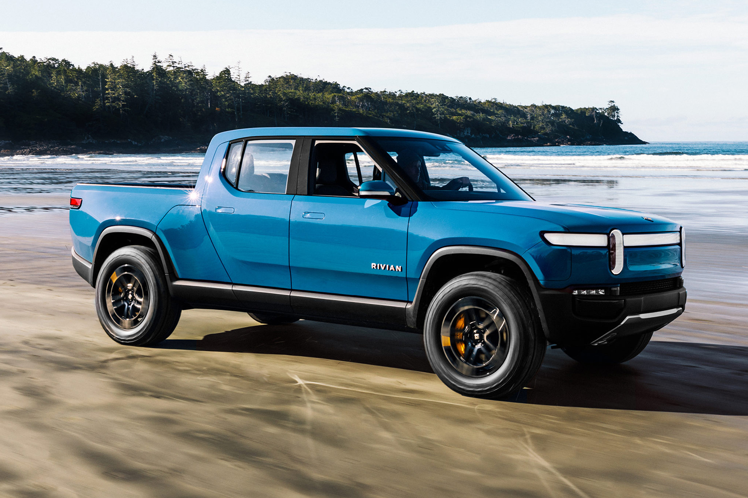 The Rivian R1T electric truck driving on the beach