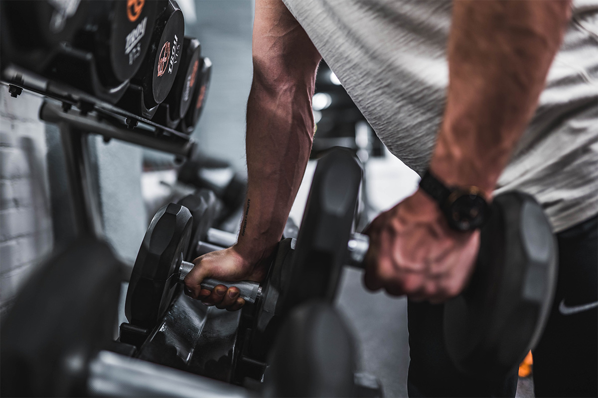 man lifting dumbbells off a weight rack in a gym