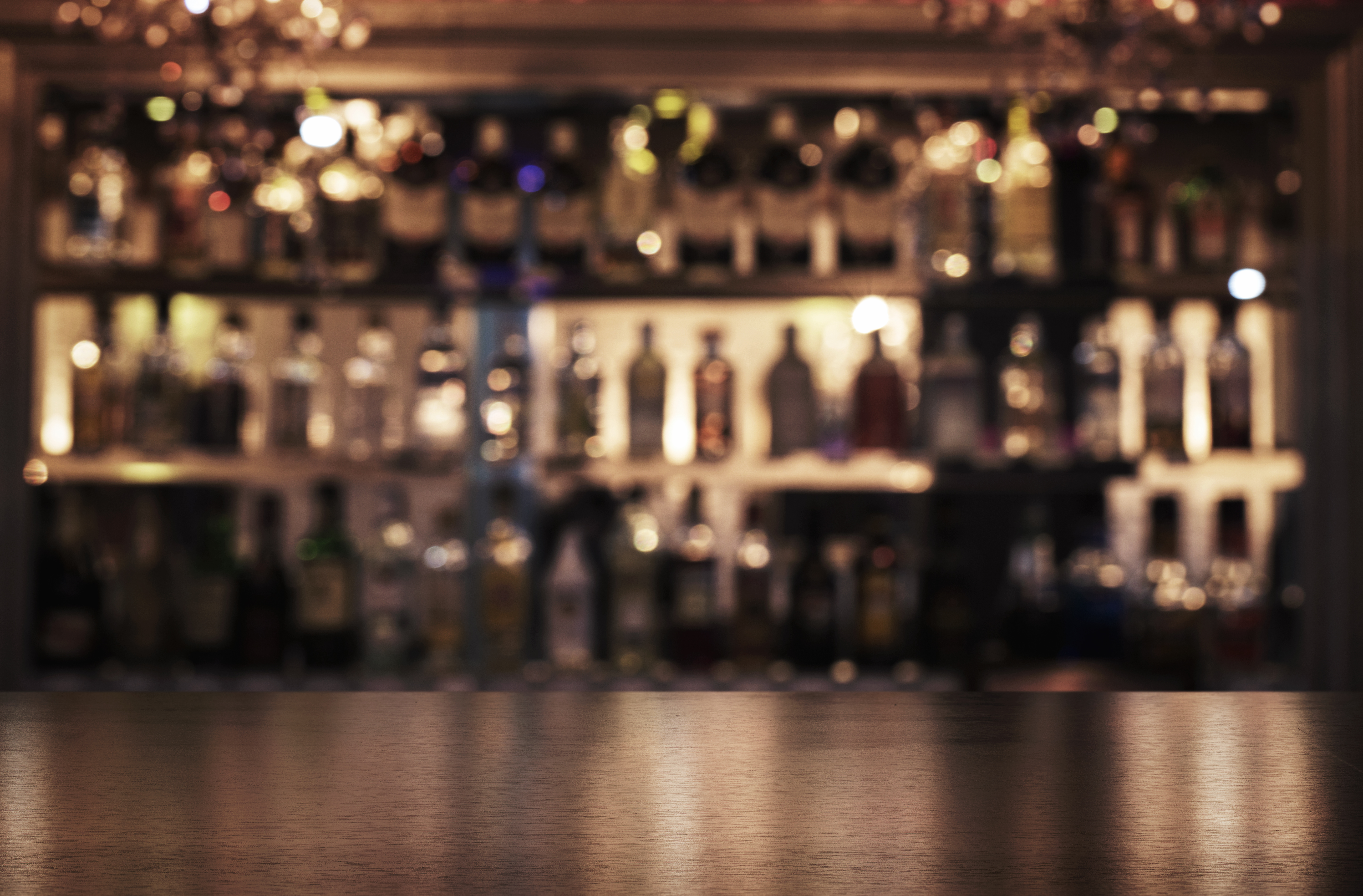 empty wooden bar with booze in the background