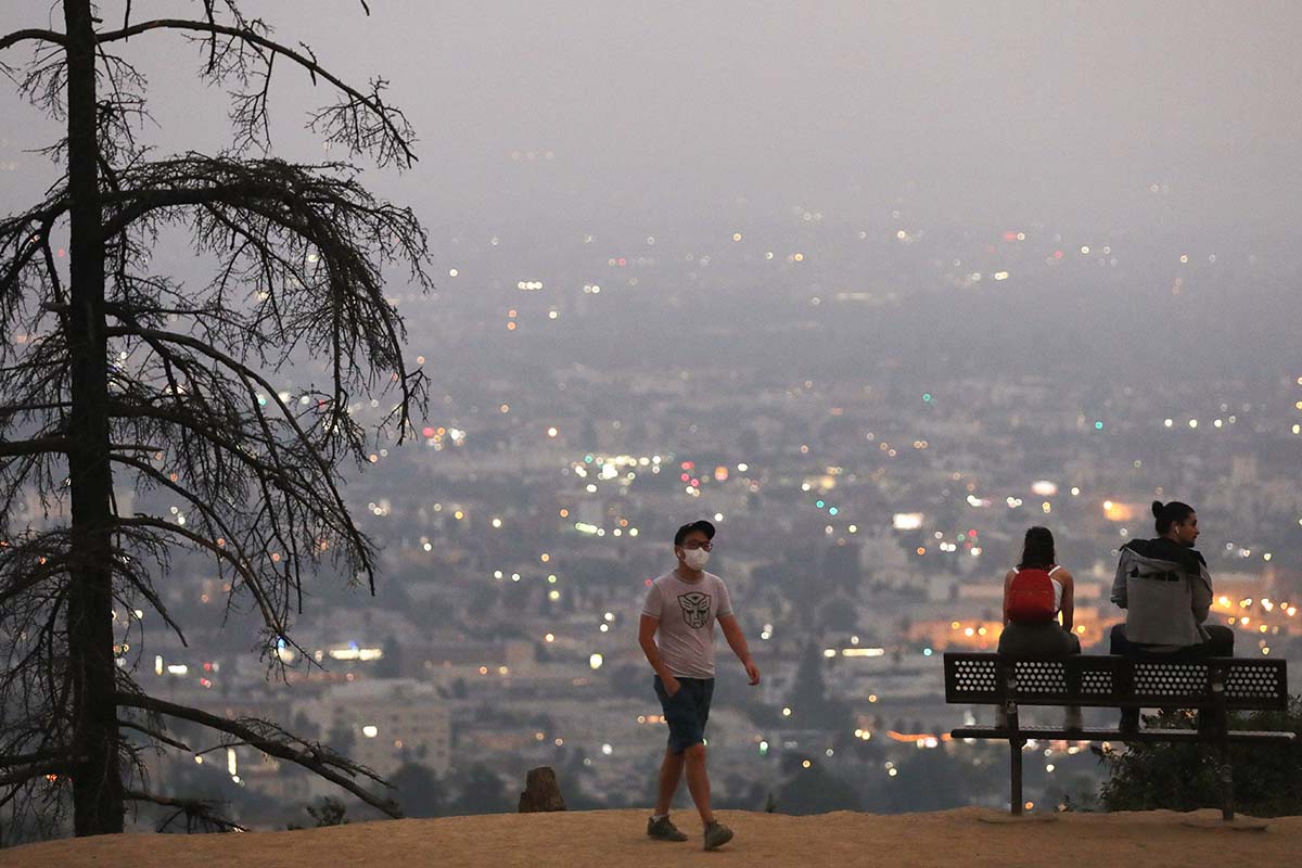 man walking amongst smoke from the wildfires in Los Angeles