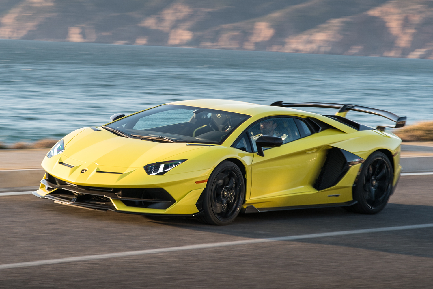 A Lamborghini Aventador SVJ car driving next to the ocean