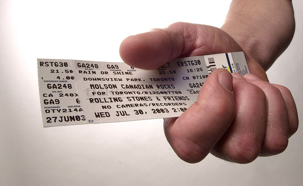 A hand holding a concert ticket