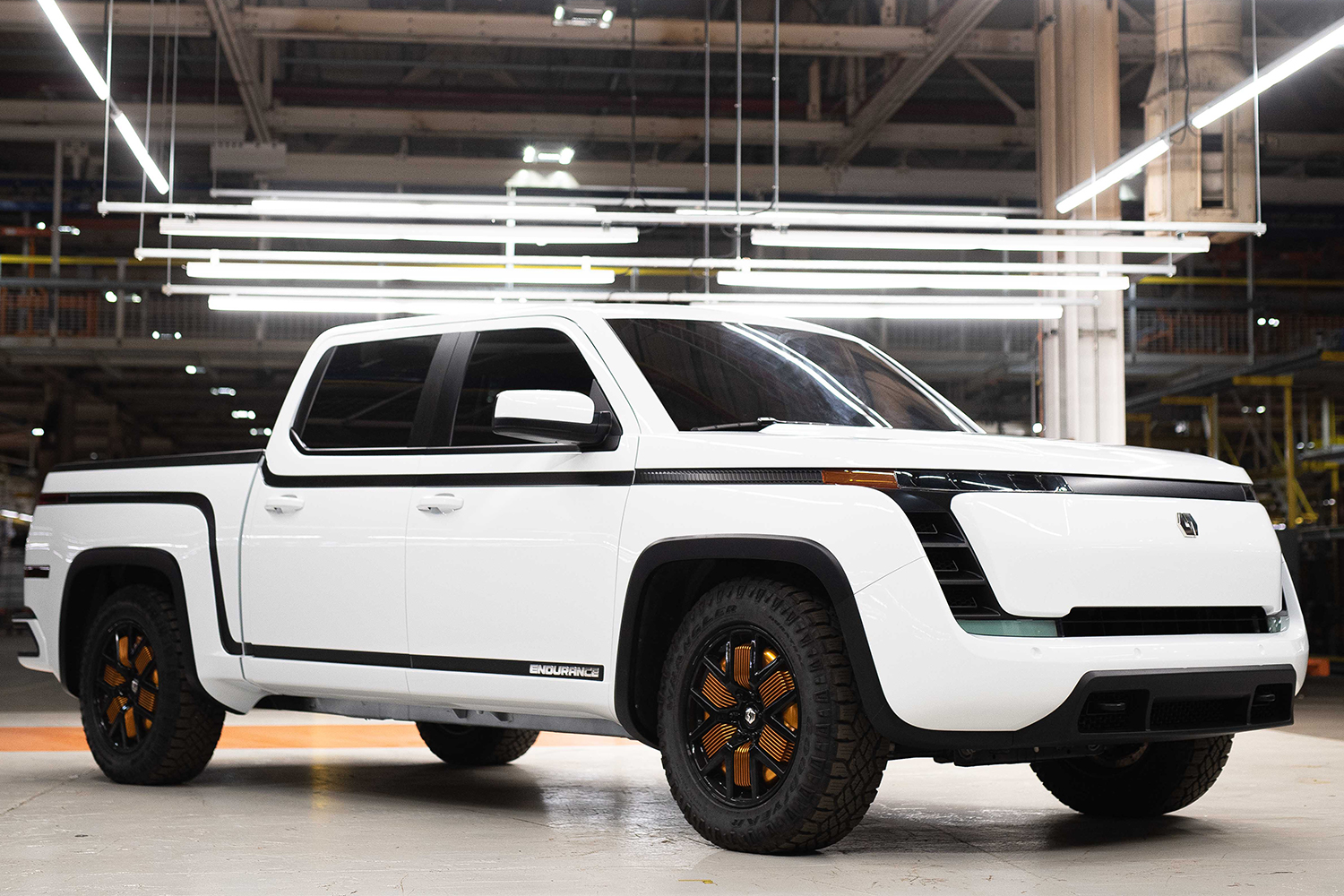 A white electric Endurance pickup truck from Lordstown Motors sitting in a warehouse under lights