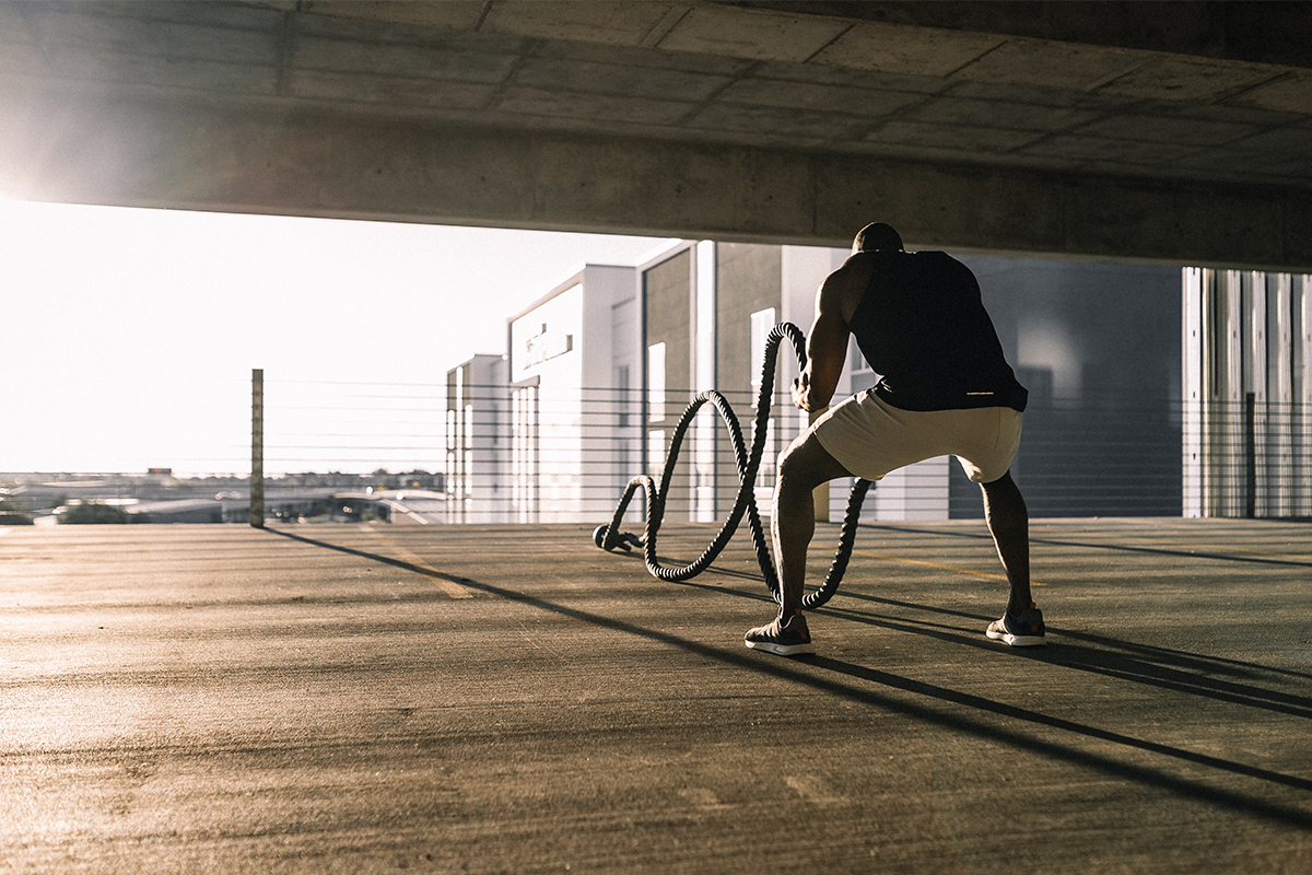 A man doing a HIIT workout by swinging battle ropes up and down