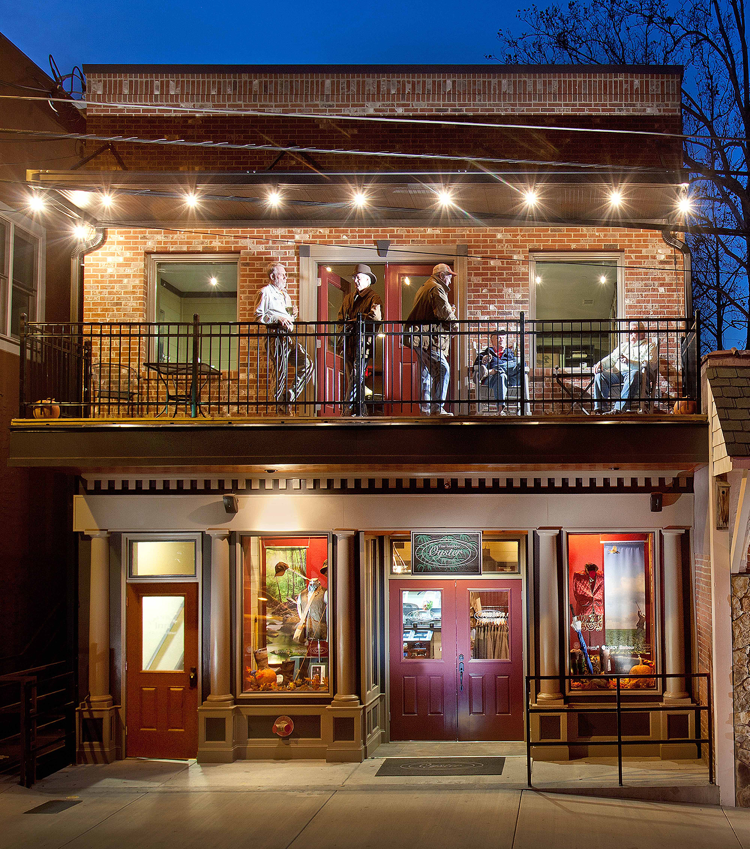 The front of the Oyster Bamboo Fly Rods building in Blue Ridge, Georgia, with people sitting on a second story balcony under string lights